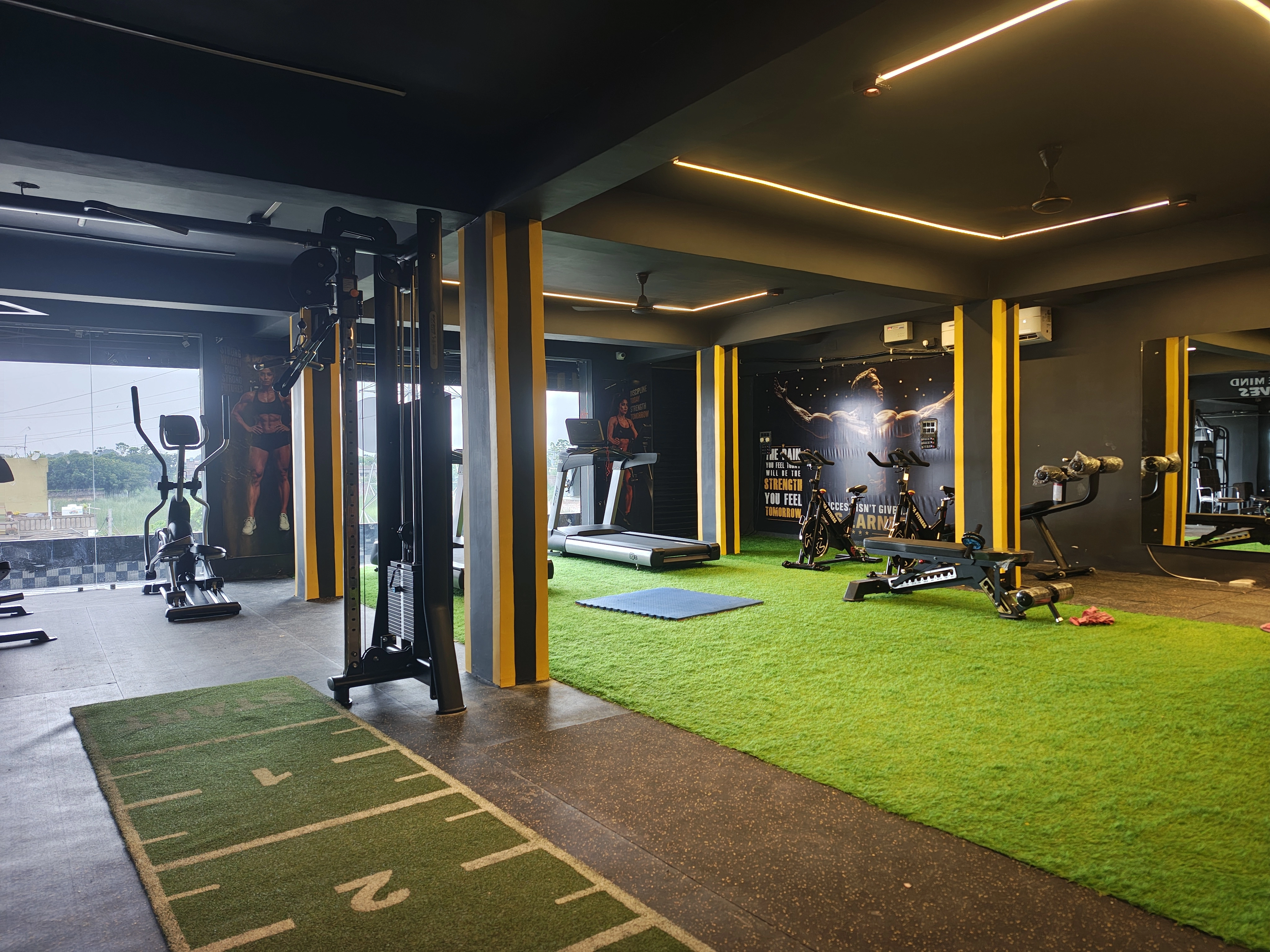 Wide view of the Arnold Gym workout floor with treadmills, spin bikes and wall art